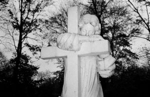 Angel holding cross sign over grave