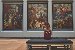 Lady sitting on a chair watching three art pictures